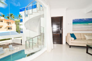 living room with view of large window showing the pool and spiral staircase at second floor condo at The SANCTUARY at Los Corales