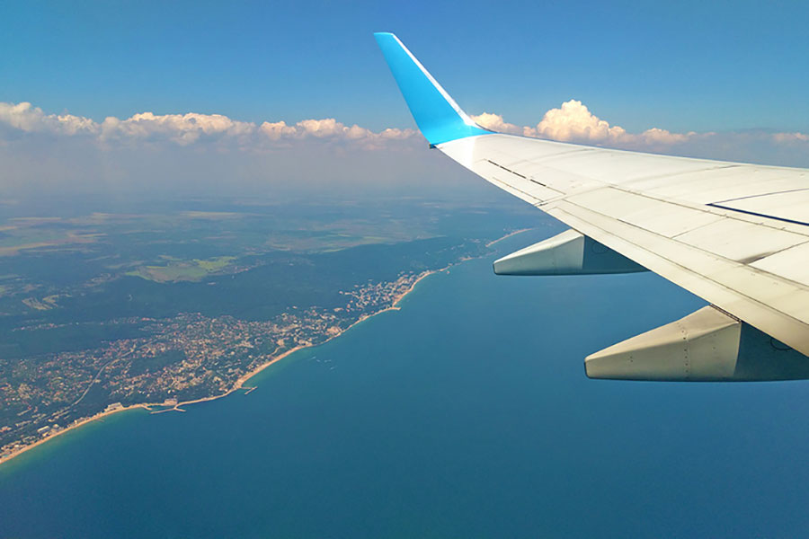 Airplane wing view out of the window on the cloudy sky The Earth and the blue sea background